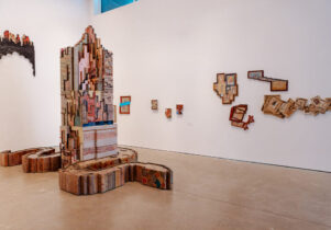 A pillar sculpture with photos of architecture in the middle of the gallery