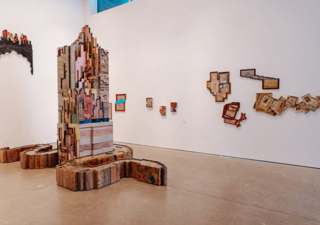 A pillar sculpture with photos of architecture in the middle of the gallery