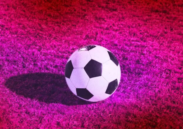 Football against a pink filtered grass pitch