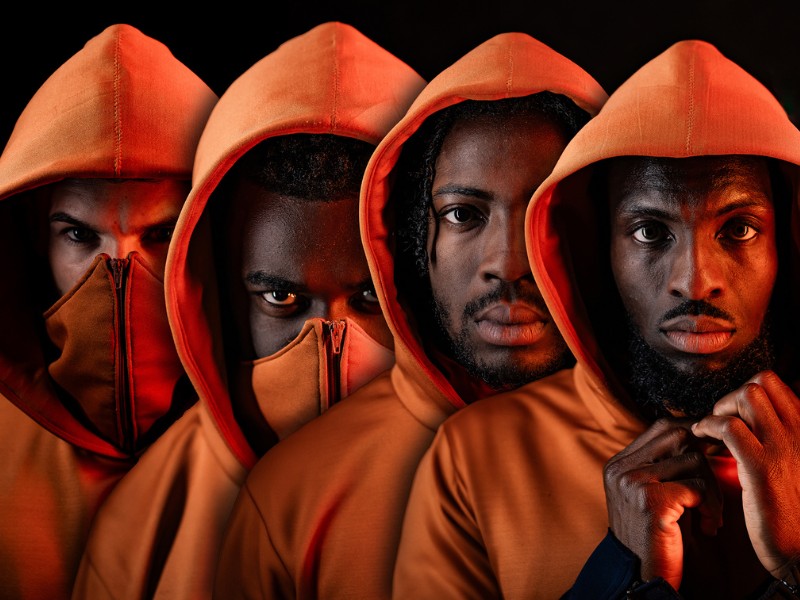 Four people wearing orange hooded jumpers.