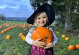 Girl holding a pumpkin in a field in the evening