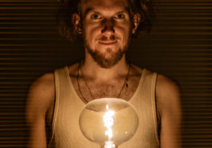 Helios at George Street Chapel: Man staring front, lit by an incandescent light