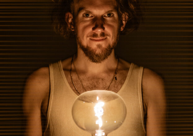 Helios at George Street Chapel: Man staring front, lit by an incandescent light