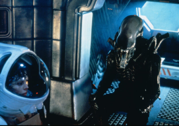 Boy in space suit looking at alien.