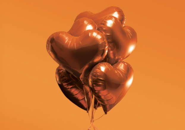 An orange background with dark orange balloons in the shape of hearts.