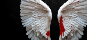 A pair of white angel wings displayed against a dark, black background. The lower parts of the wings are stained with vivid red, resembling blood splatter.