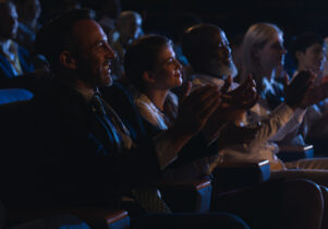 Side view of mixed race business colleagues sitting and watching presentation with audience and clapping hands