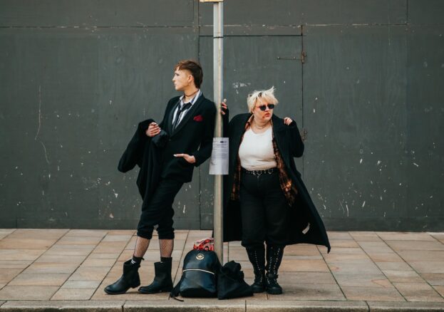 Two goths standing at a bus stop