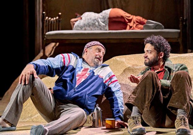 Two actors performing on stage. They are both sat on the floor.