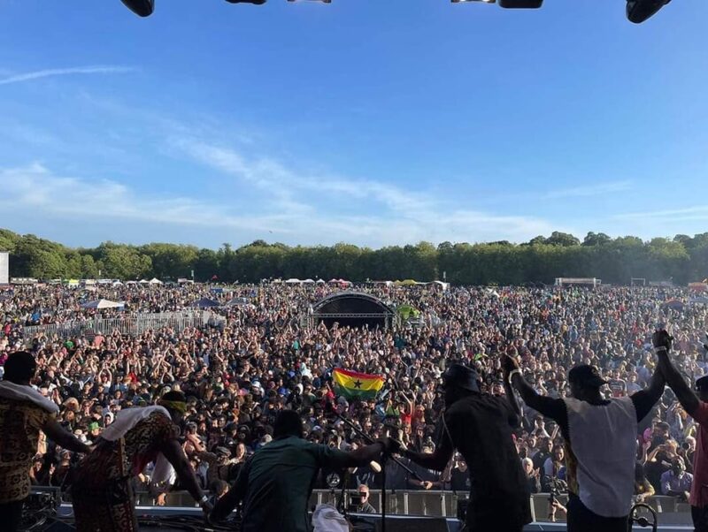 A band taking a bow in front of a packed festival crowd.